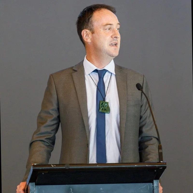 Man in a suit speaking at a podium